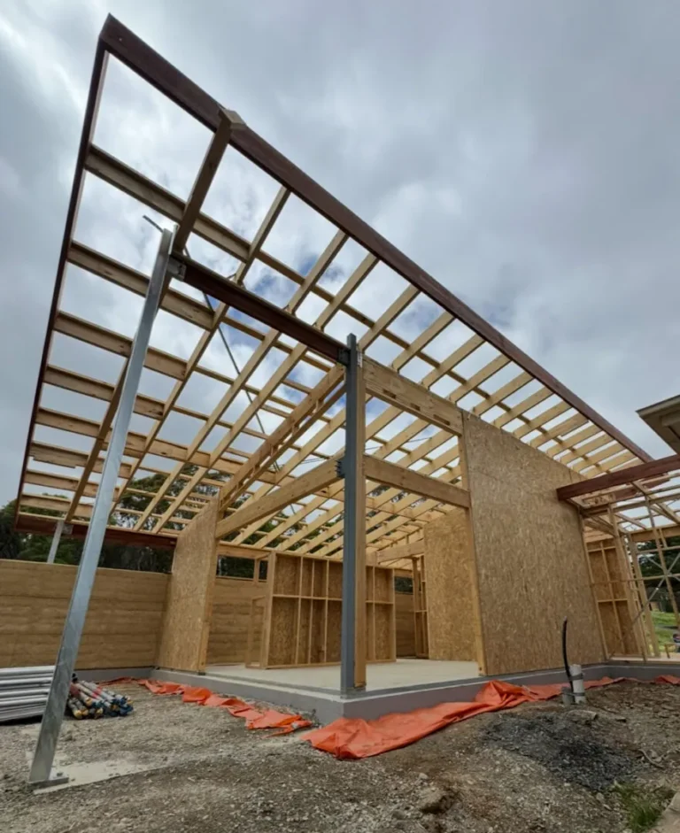 Partially constructed house framework under cloudy sky.