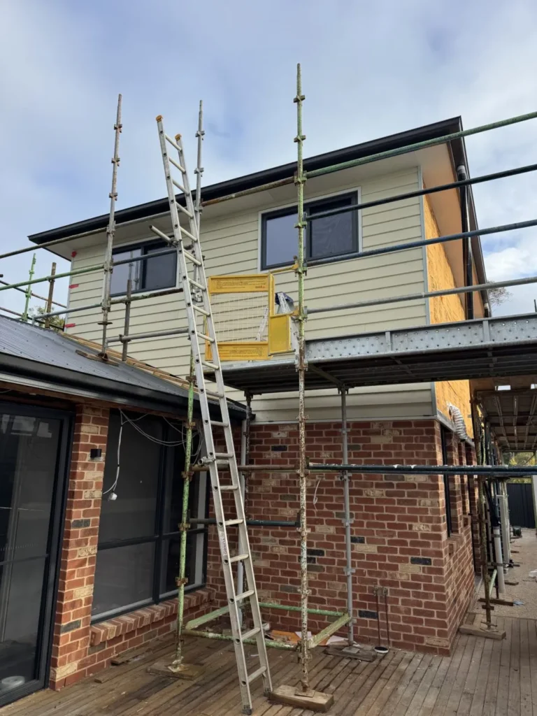 House under construction with scaffolding and ladder.